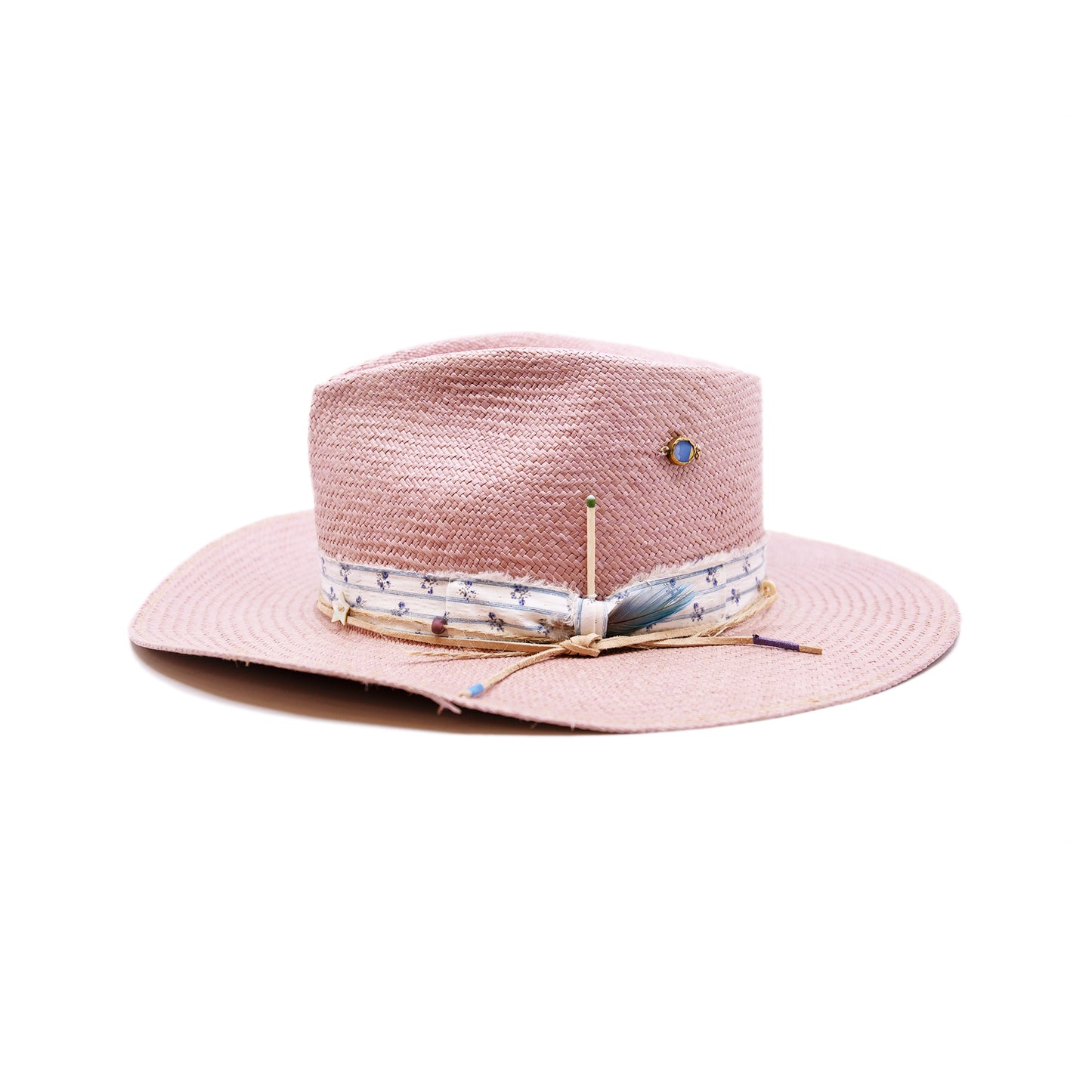 Dandelion Dixie Hwy 100% Ecuadorian straw in Blush 1” deadstock striped fabric band and bow Nude leather band and twine with accouterments and color accents Molt-harvested parrot feather Custom NF jewelry piece on crown Woven in Ecuador Subtle western flanged brim Made in USA