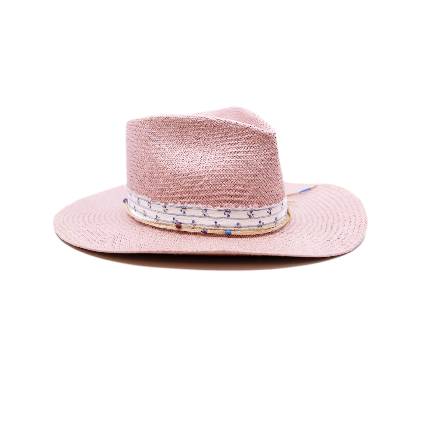 Dandelion Dixie Hwy 100% Ecuadorian straw in Blush 1” deadstock striped fabric band and bow Nude leather band and twine with accouterments and color accents Molt-harvested parrot feather Custom NF jewelry piece on crown Woven in Ecuador Subtle western flanged brim Made in USA