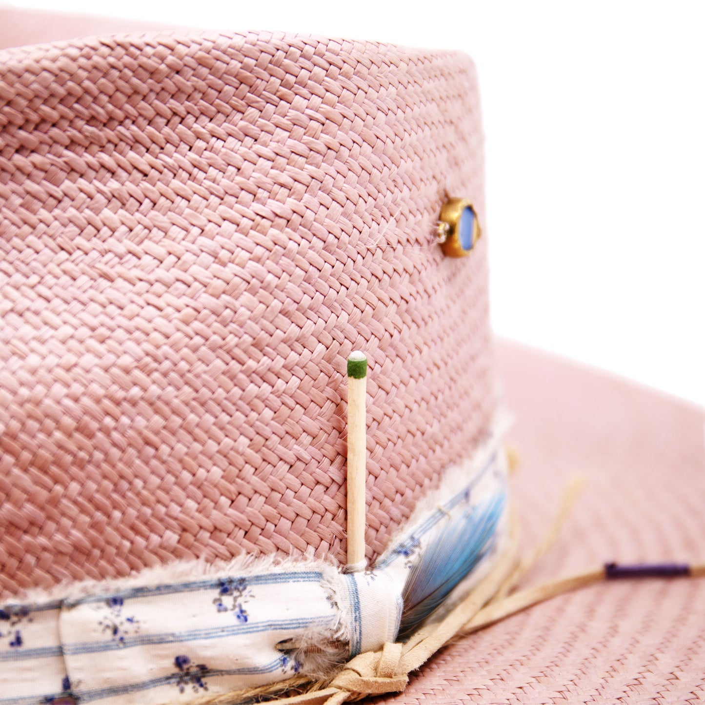 Dandelion Dixie Hwy 100% Ecuadorian straw in Blush 1” deadstock striped fabric band and bow Nude leather band and twine with accouterments and color accents Molt-harvested parrot feather Custom NF jewelry piece on crown Woven in Ecuador Subtle western flanged brim Made in USA