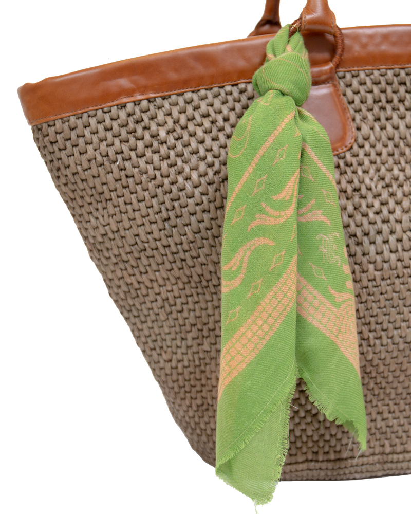 Mer Vert Ecuadorian straw tote bag with brown vachetta leather trim and a green patterned scarf tied to the handle.