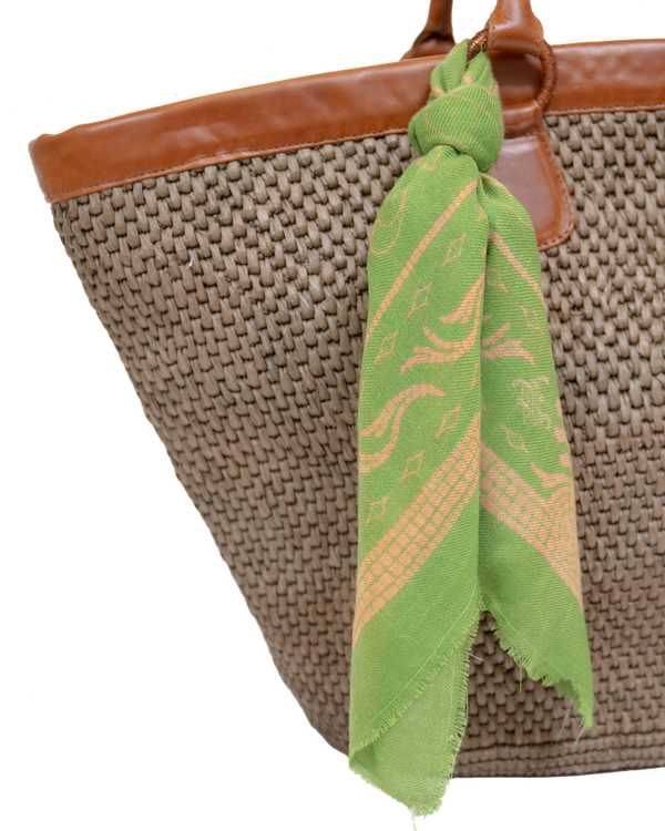 Mer Vert Ecuadorian straw tote bag with brown vachetta leather trim and a green patterned scarf tied to the handle.