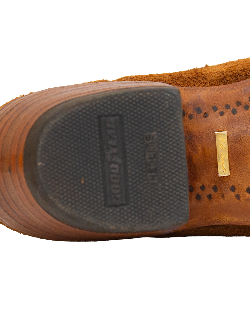 The heel and sole of a whiskey brown Serpent Cutter boot, featuring a rubber heel cap embossed with Goodyear and a small gold-tone metal plate embedded in the leather sole.