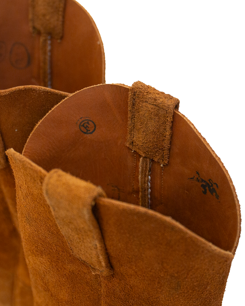 Close-up of the interior and top opening of a whiskey brown suede Serpent Cutter western-style boot, showing leather pull tabs and printed markings.