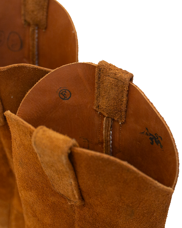 Close-up of the interior and top opening of a whiskey brown suede Serpent Cutter western-style boot, showing leather pull tabs and printed markings.
