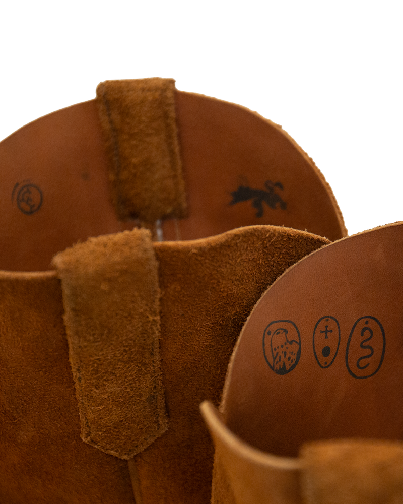 Interior view of two whiskey brown roughout hide Silo Roper boots, featuring embossed circular symbols on the inner lining.
