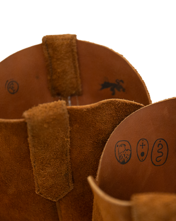 Interior view of two whiskey brown roughout hide Silo Roper boots, featuring embossed circular symbols on the inner lining.