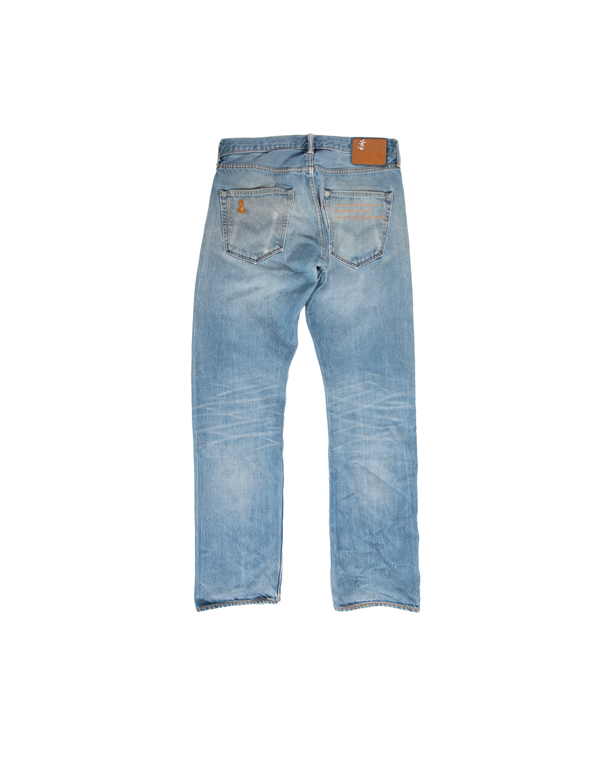 Back view of Venice-Store Cote Savauge Denim in light-wash, featuring hand-embroidered orange artwork on the back pockets and a tan leather patch on the waistband.