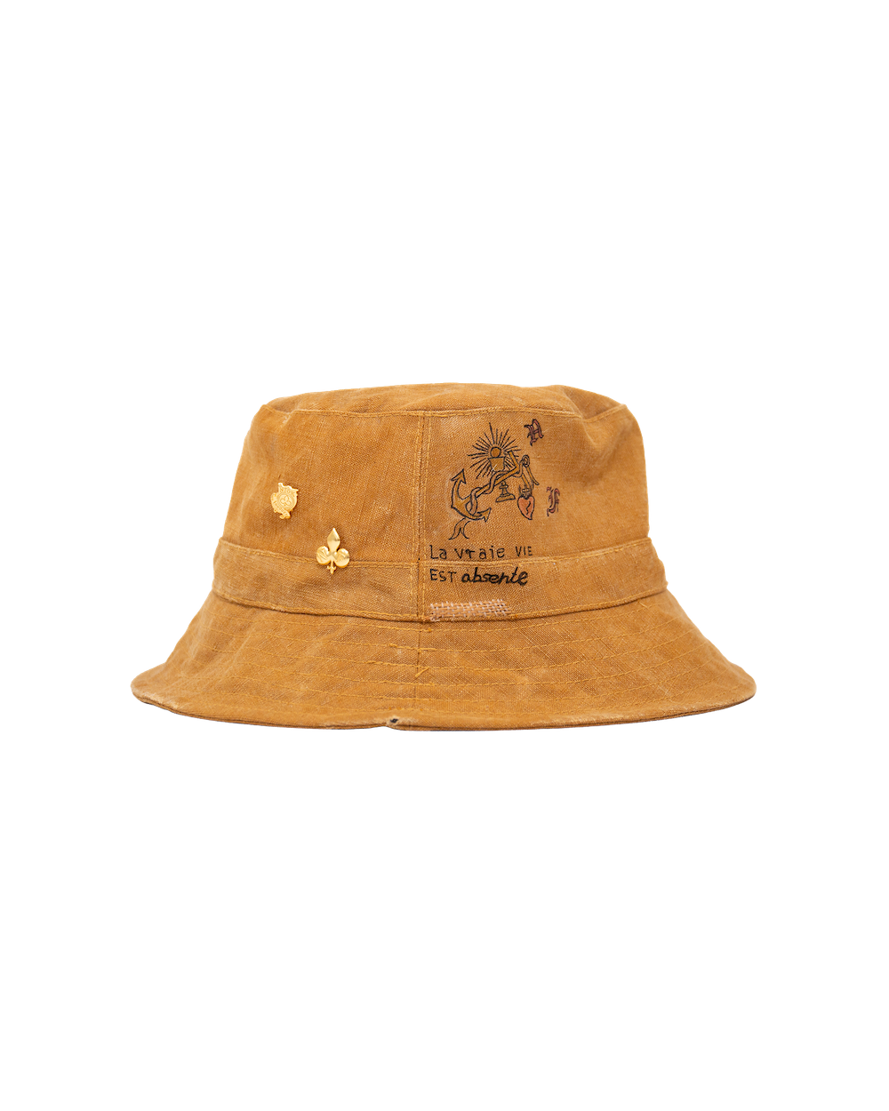 Sage Bucket in tan waxed canvas, adorned with small gold-plated pins, an anchor embroidery, and the French text La vraie vie est absente.