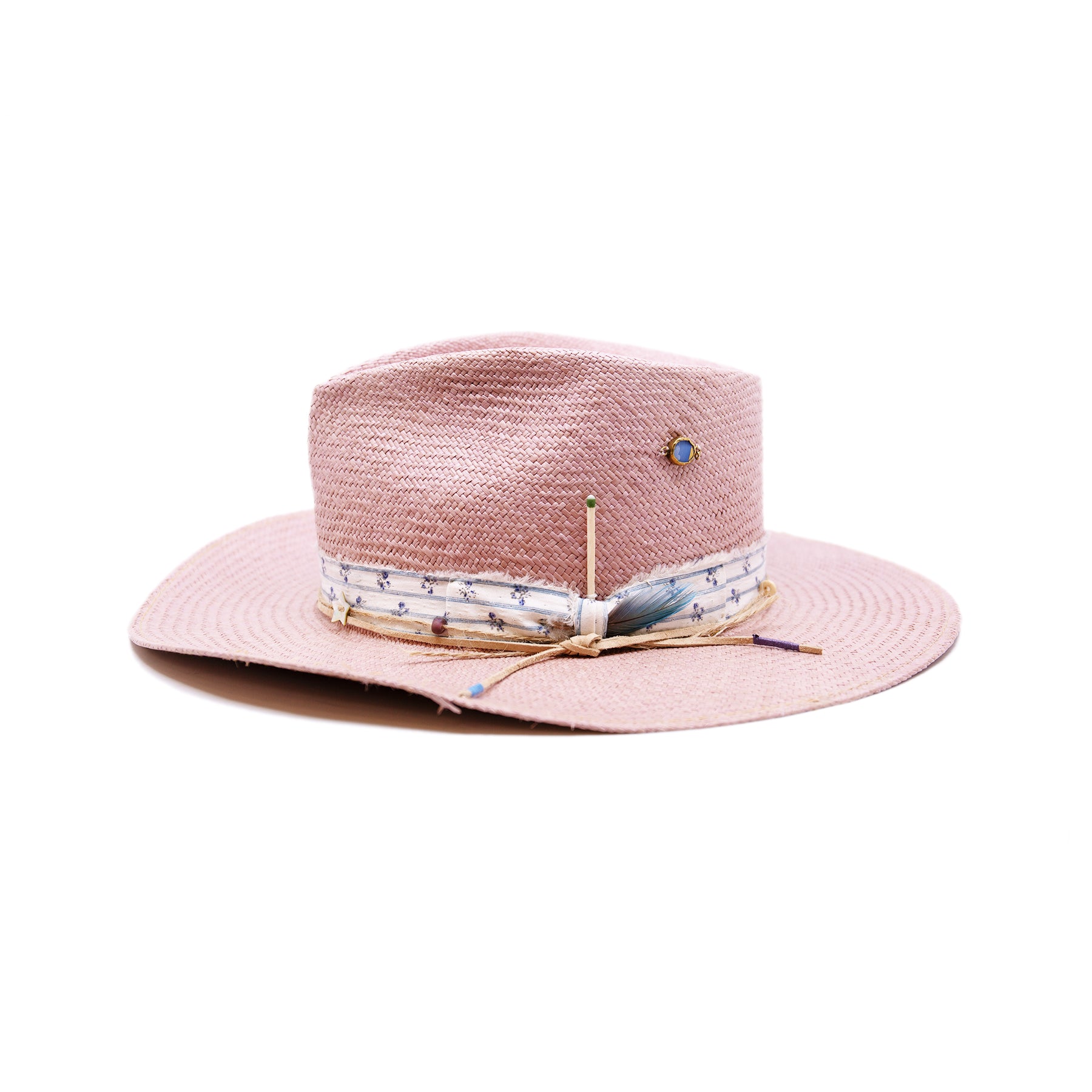 Dandelion Dixie Hwy  100% Ecuadorian straw in Blush  1” deadstock striped fabric band and bow  Nude leather band and twine with accouterments and color accents  Molt-harvested parrot feather  Custom NF jewelry piece on crown  Woven in Ecuador  Subtle western flanged brim  Made in USA