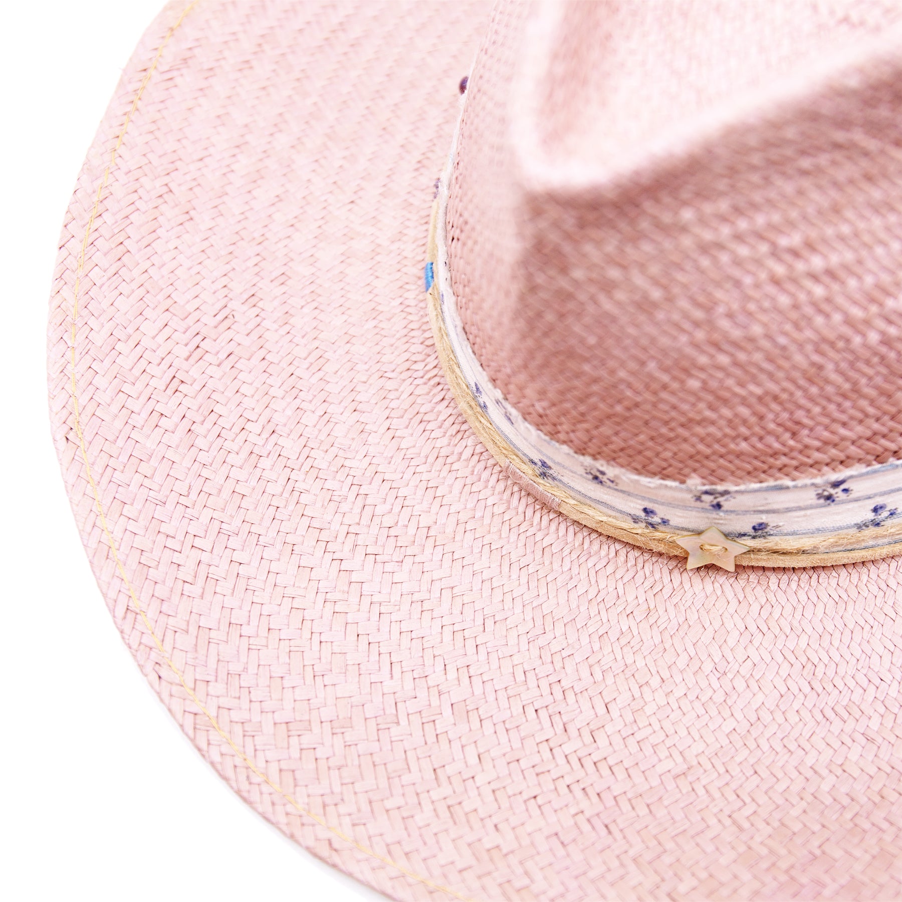 Dandelion Dixie Hwy  100% Ecuadorian straw in Blush  1” deadstock striped fabric band and bow  Nude leather band and twine with accouterments and color accents  Molt-harvested parrot feather  Custom NF jewelry piece on crown  Woven in Ecuador  Subtle western flanged brim  Made in USA