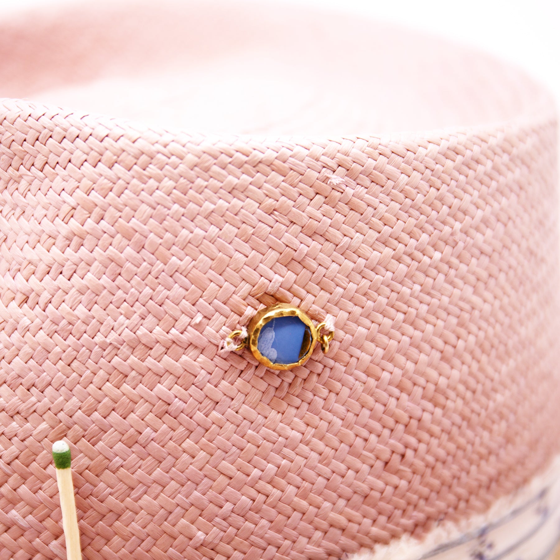 Dandelion Dixie Hwy  100% Ecuadorian straw in Blush  1” deadstock striped fabric band and bow  Nude leather band and twine with accouterments and color accents  Molt-harvested parrot feather  Custom NF jewelry piece on crown  Woven in Ecuador  Subtle western flanged brim  Made in USA