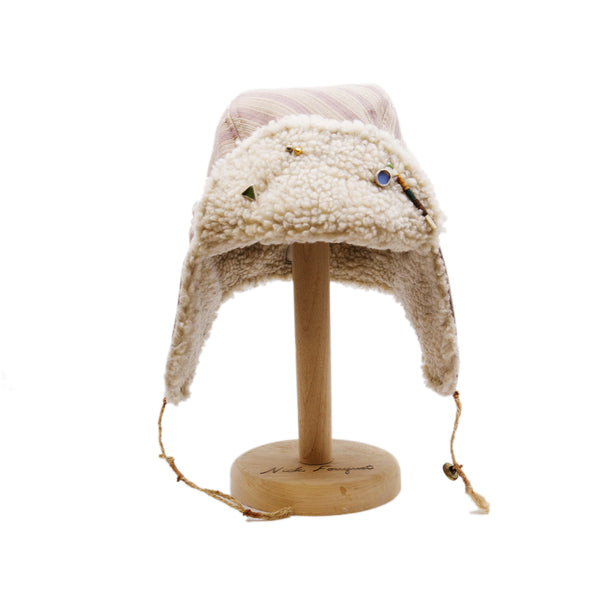 Snowmass Trapper Hat  Shearling Cotton   Braided twine and metallic button closure  Gold plated and ceramic accouterments will vary from hat to hat  Made in Los Angeles