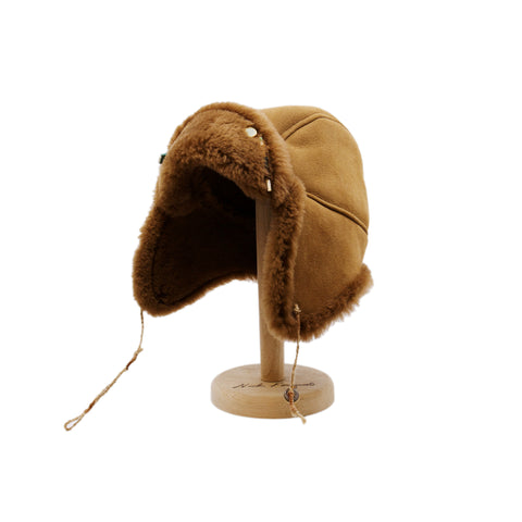 Aspen Highlands Trapper Hat Shearling Leather  Braided twine and metallic button closure  Gold plated and ceramic accouterments will vary from hat to hat  Made in Los Angeles