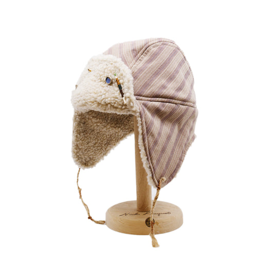 Snowmass Trapper Hat  Shearling Cotton   Braided twine and metallic button closure  Gold plated and ceramic accouterments will vary from hat to hat  Made in Los Angeles